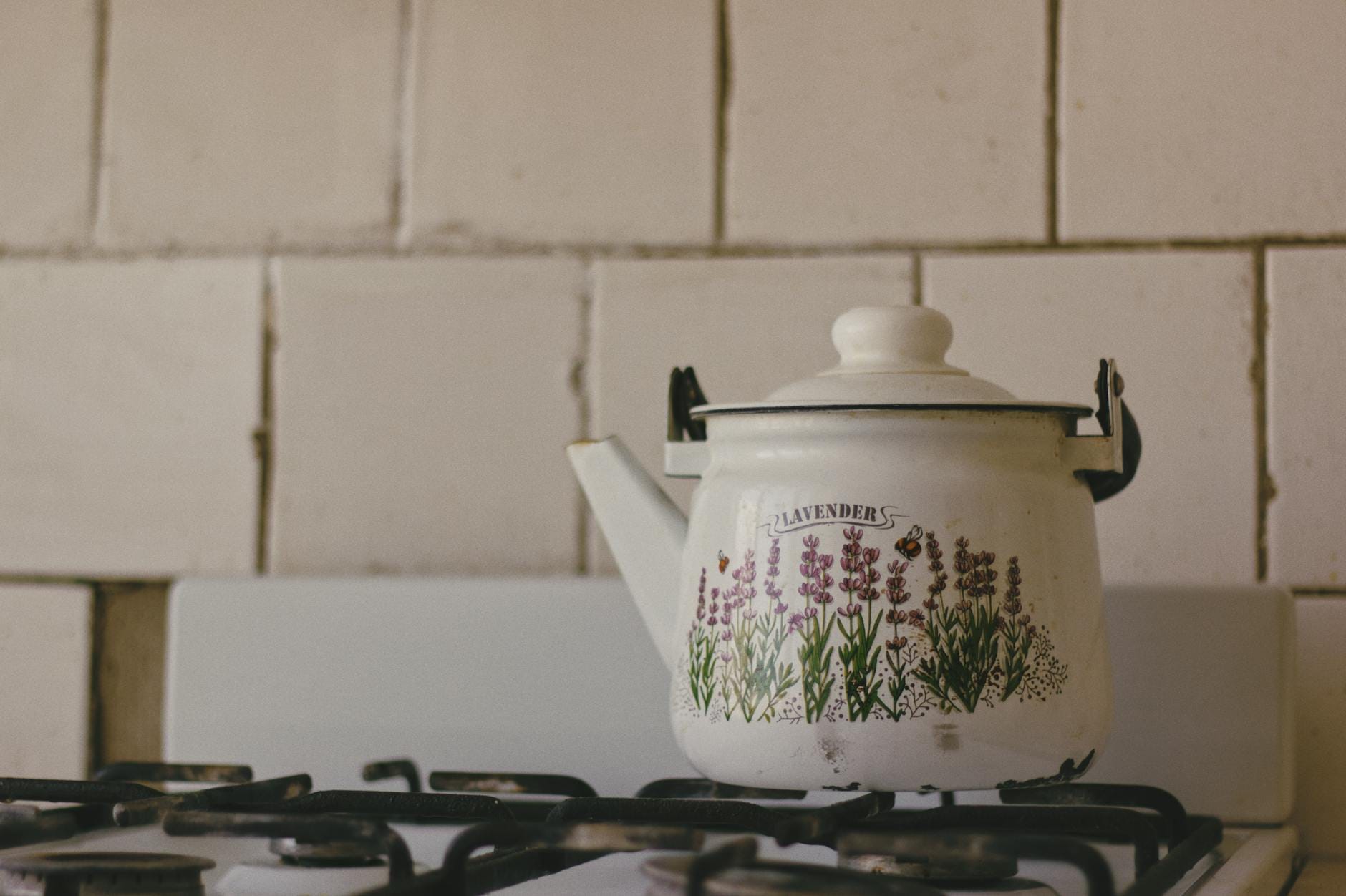 Emaliowany czajnik w lawendowy wzór stojący na kuchence gazowej